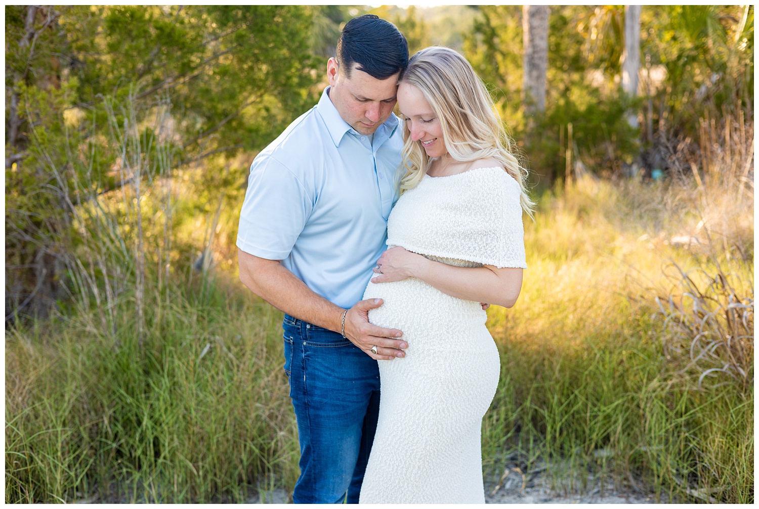 Couple maternity photo in coastal Georgia with expecting parents holding baby bump in soft golden light during outdoor session