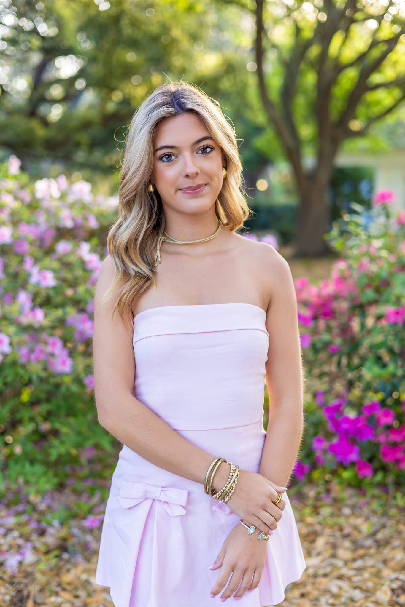 A high school senior stands in a pink flower garden smiling in a matching pink dress after some SAT prep in Savannah, GA