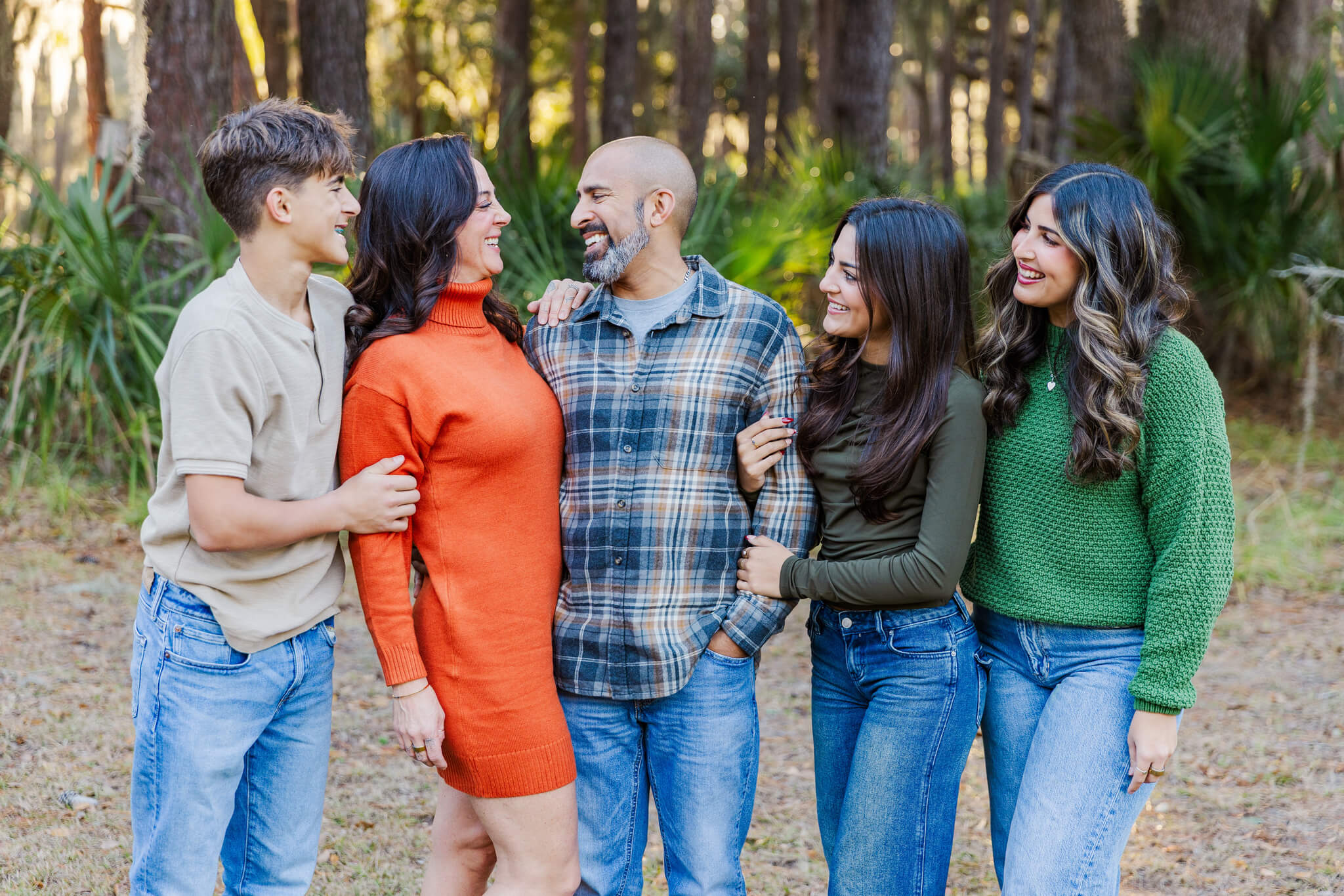 A family with three adult children laughs at mom and dad while standing in a park in fall after finding couples activities in savannah ga