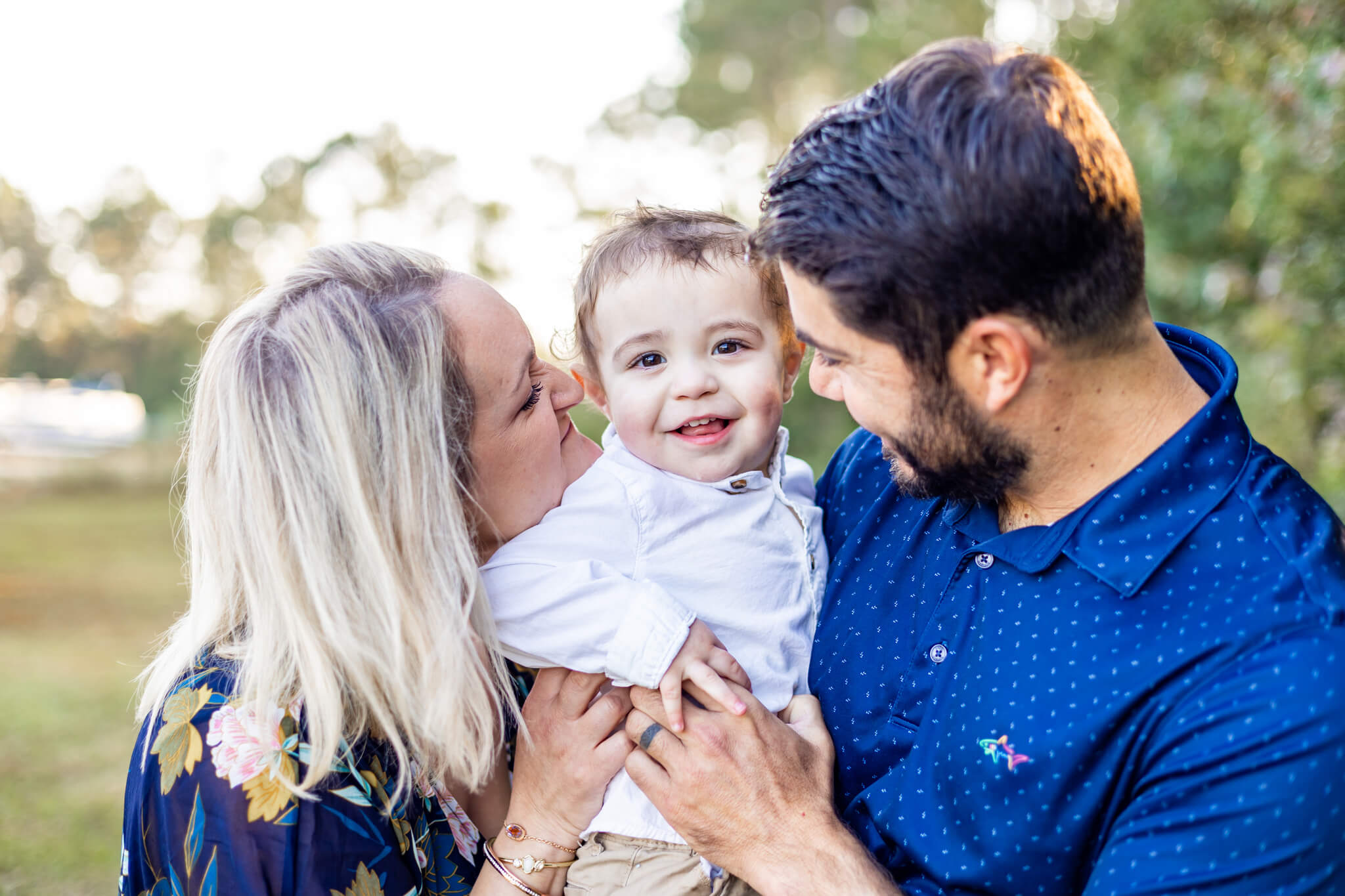 Happy mom and dad tickle and smile at their happy toddler held between them tnks to marriage counseling in savannah