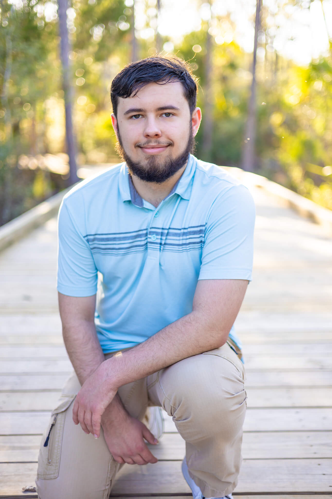 A teenager kneels in a blue polo and khakis on a wooden boardwalk at sunset after finding tutoring in Pooler, GA