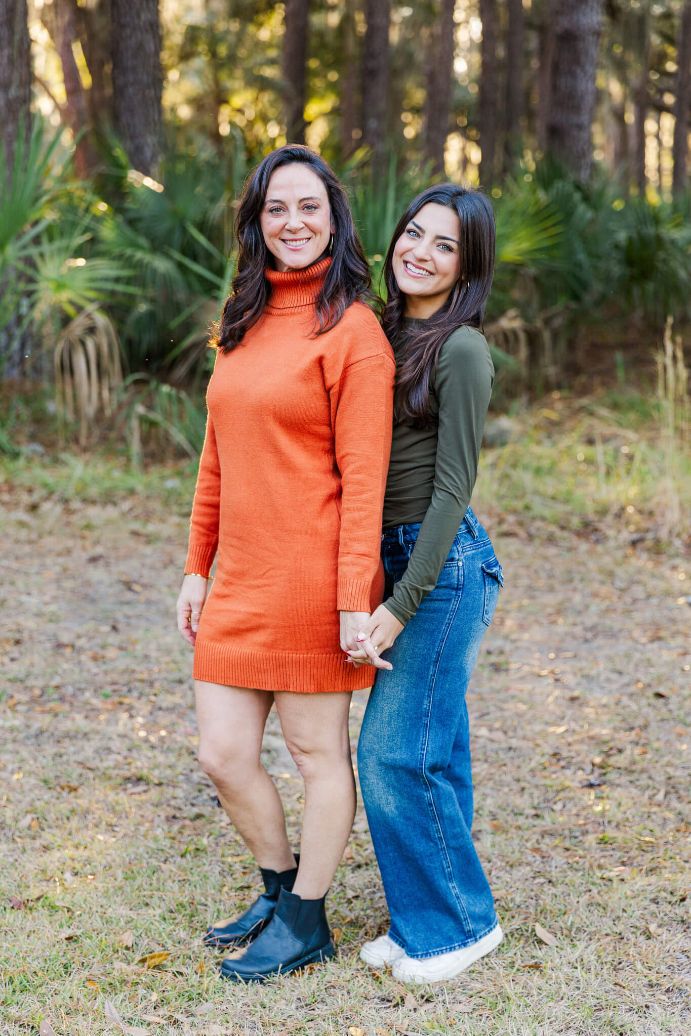 A smiling mother in orange holds hands with her teen daughters in a park after planning a date night in Pooler, GA