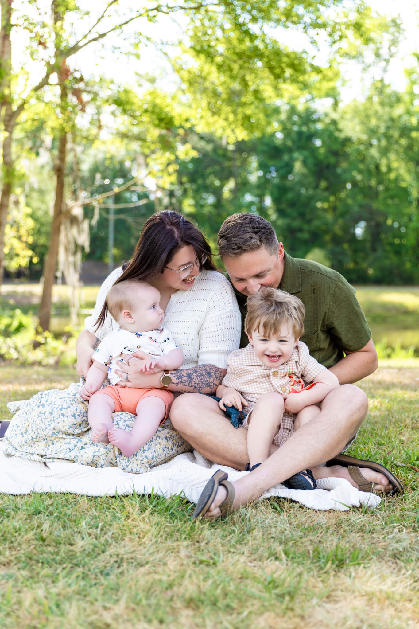 Happy mom and dad thriving after marriage counseling in pooler, ga while playing with their two toddlers in a park lawn
