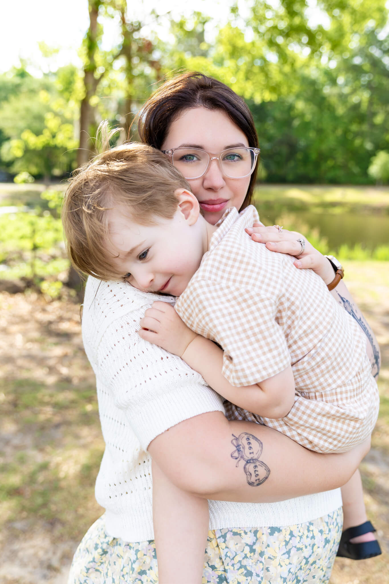 A mother in a floral dress and white sweater smiles while holding her toddler son after benefiting from marriage counseling in pooler, ga