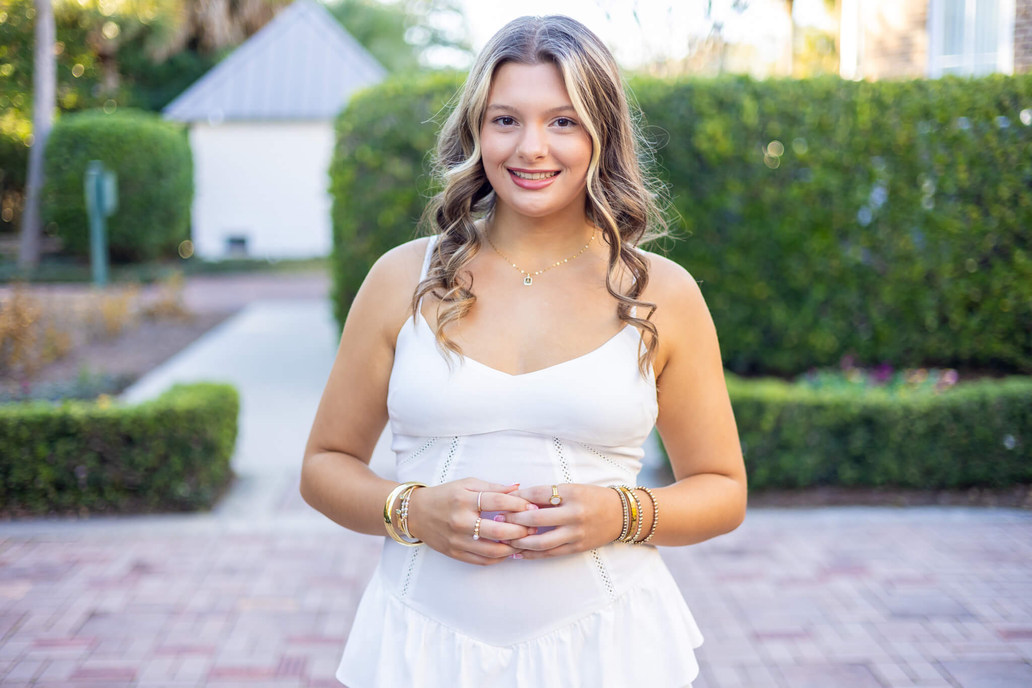 A smiling woman in a white dress standing in a garden patio