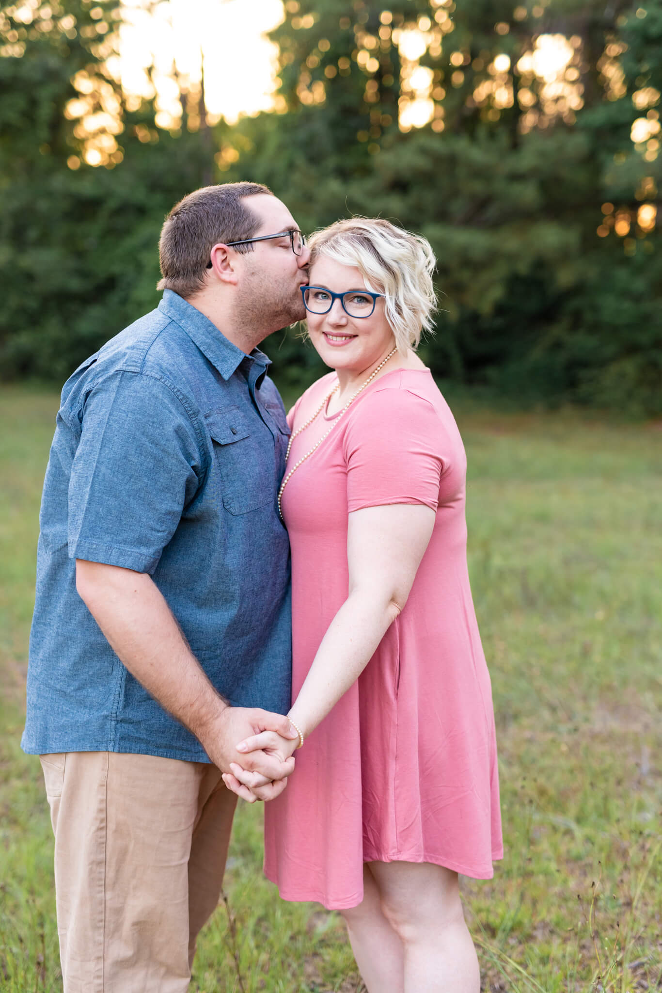 A happy couple stand holding hands in a field at sunset after enjoying some date ideas in Richmond Hill, GA