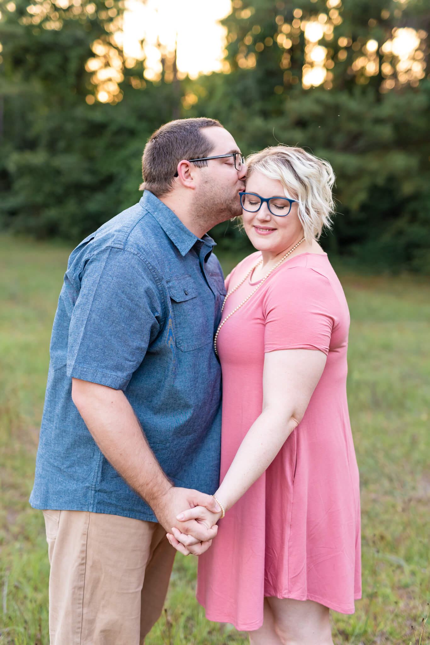 A happy couple kisses and holds hands while in a park at sunset before exploring some romantic restaurants in richmond hill, GA