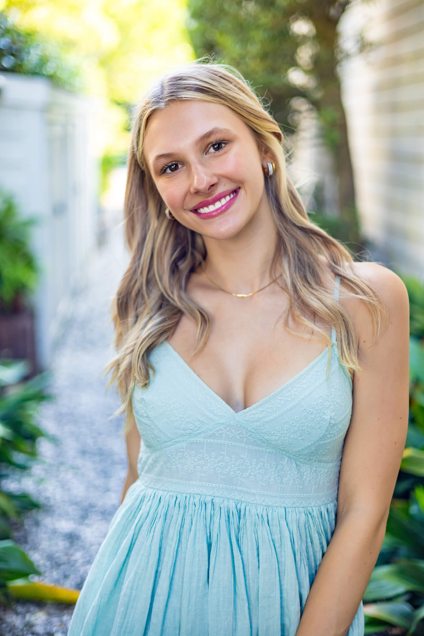 A smiling blonde high school senior in a blue sun dress walking in an alley after shopping boutiques in brunswick ga