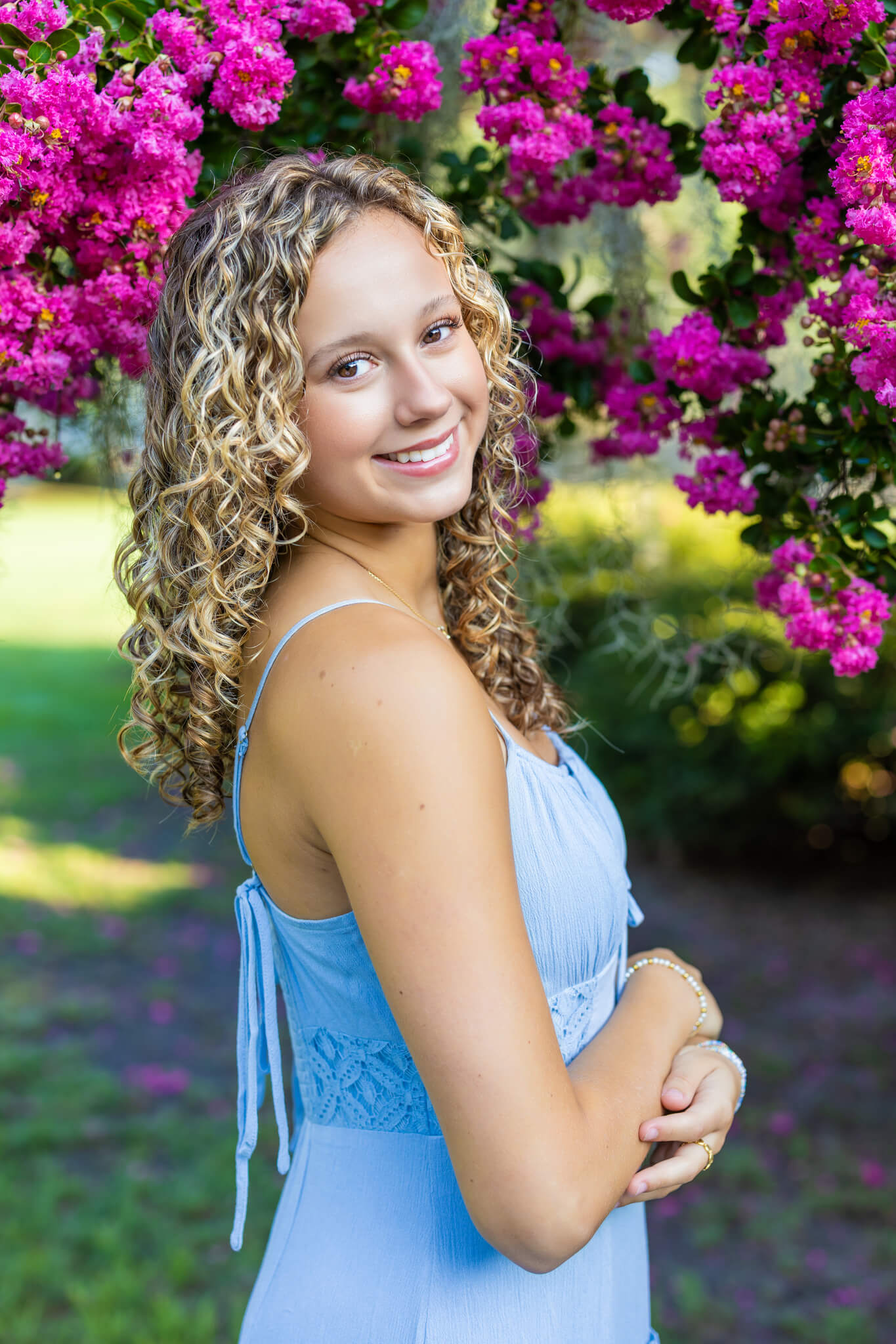 A happy woman smiling over her shoulder with arms crossed in a blue dress